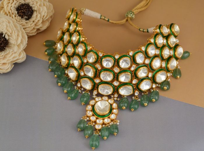 Close-up of an ornate Polki gold necklace with emerald detailing