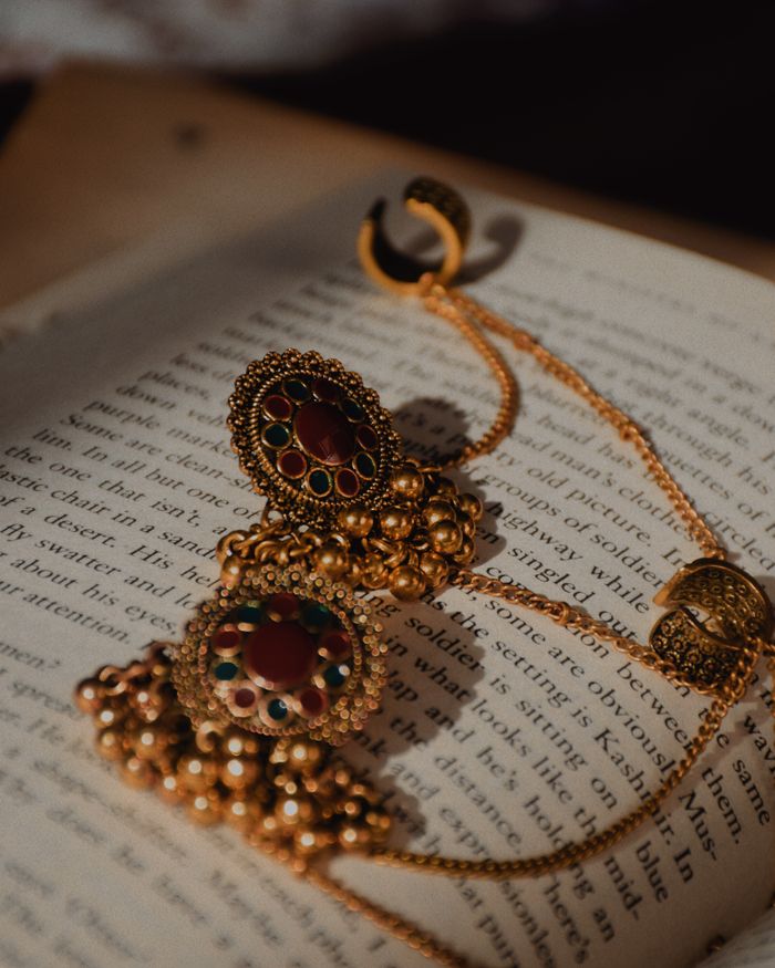 Ornate gold earrings with gemstones resting on an open book