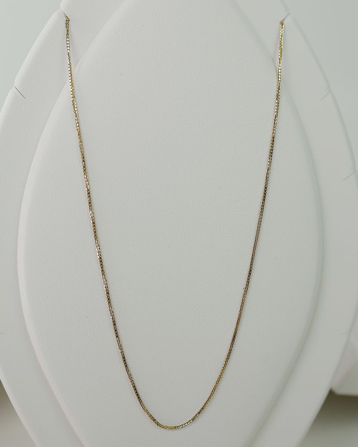 Gold necklace displayed on a minimalist jewellery stand