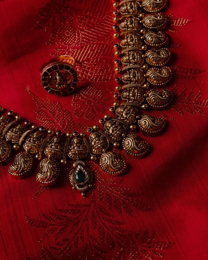 Intricate traditional gold jewellery displayed on rich red fabric